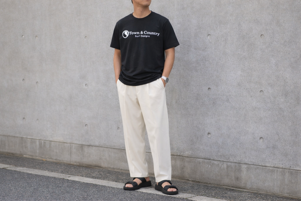 タウンアンドカントリーの黒Tシャツに白スラックスとサンダルを合わせた大人のシンプルコーデ例