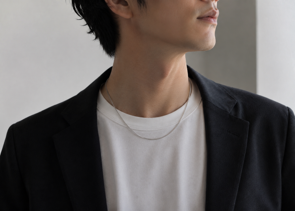 30代男性が白Tシャツとネイビージャケットに細めのシルバーネックレスを合わせたシンプルで上品なコーディネート