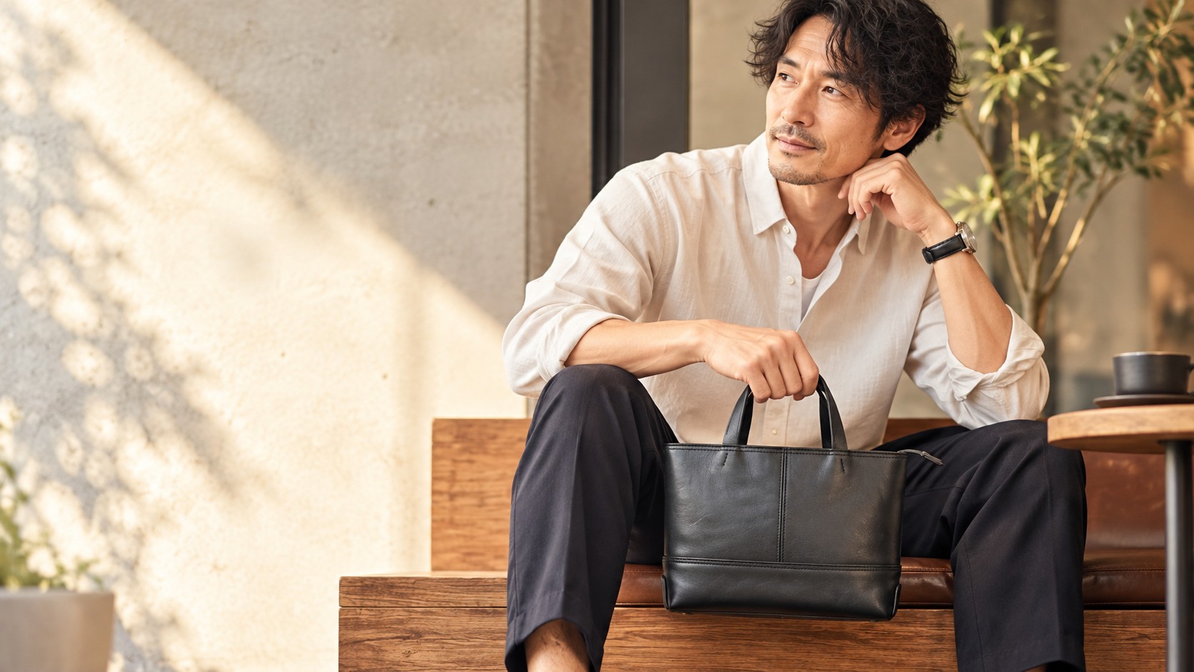 カフェのベンチに座る40代日本人男性と黒の本革ミニトートバッグb3Labo WR385のアイキャッチイメージ