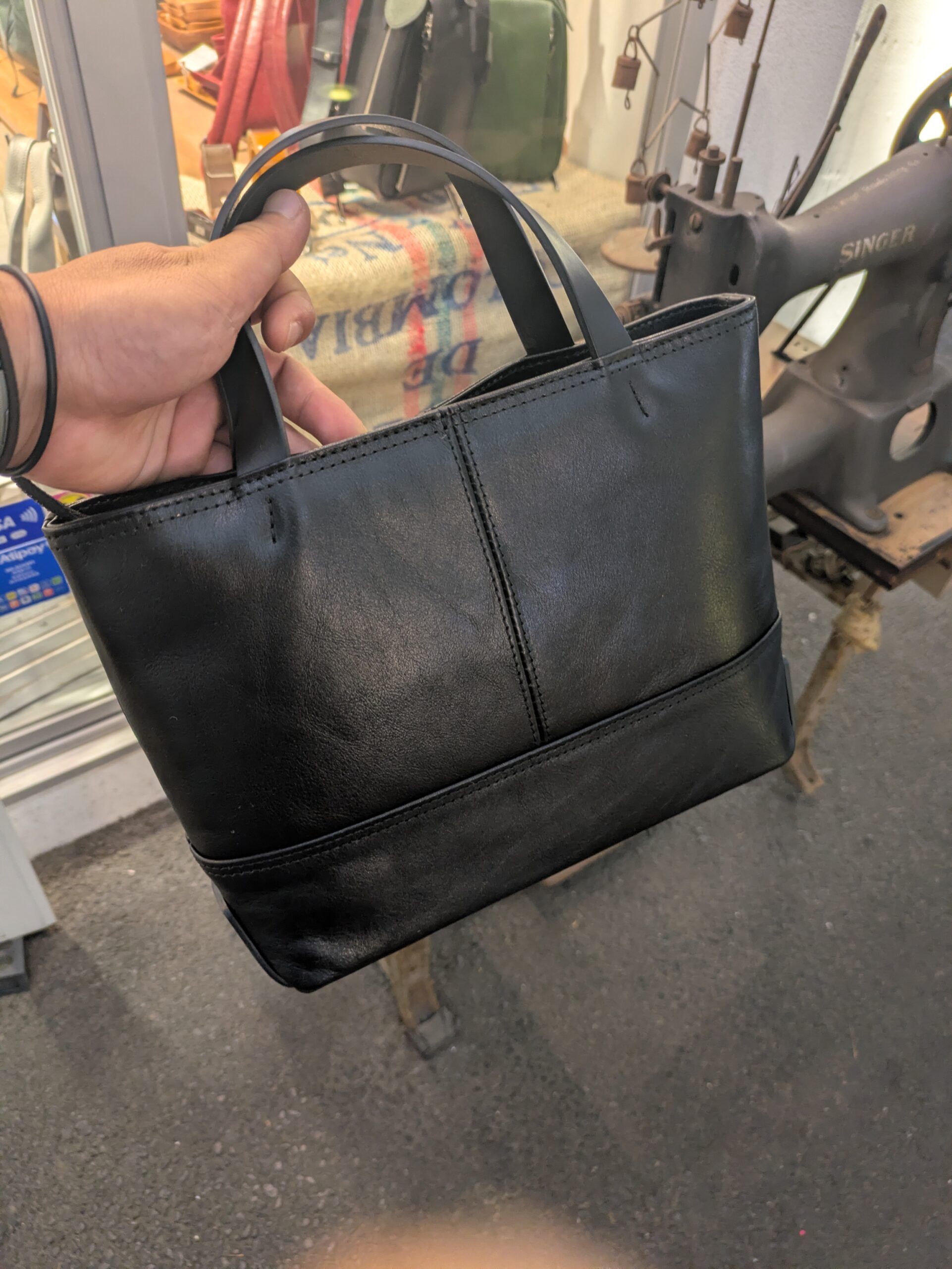 黒い本革ミニトートバッグを片手で持ったサイズ感